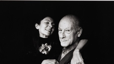 A man and a woman hug while smiling at the camera.
