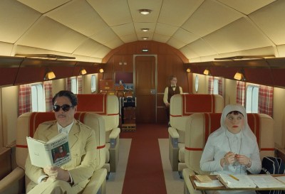 A nun and a man in a suit sitting on an empty airplane. The man can be seen reading a book on patrons in the High Renaissance.