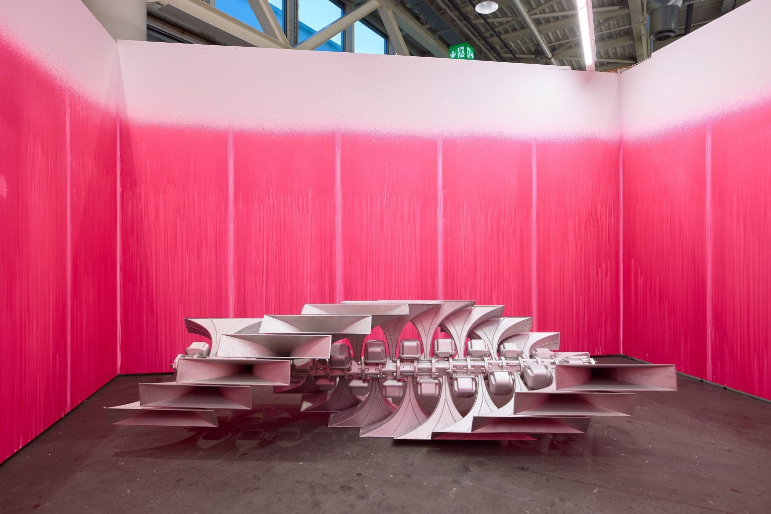 A metalic sculpture surrounded by pink walls.