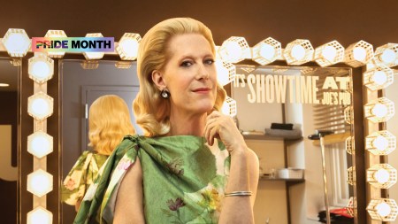 A blond woman in a green dress in front of a vanity mirror, backstage