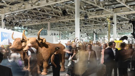 Crowds of people swirl by in a long-exposure photograph in fron tof  various artworks.