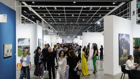 A group of people walking through the aisle of an art fair.