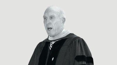 Black-and-white portrait of an older white man in a graduation doctoral gown
