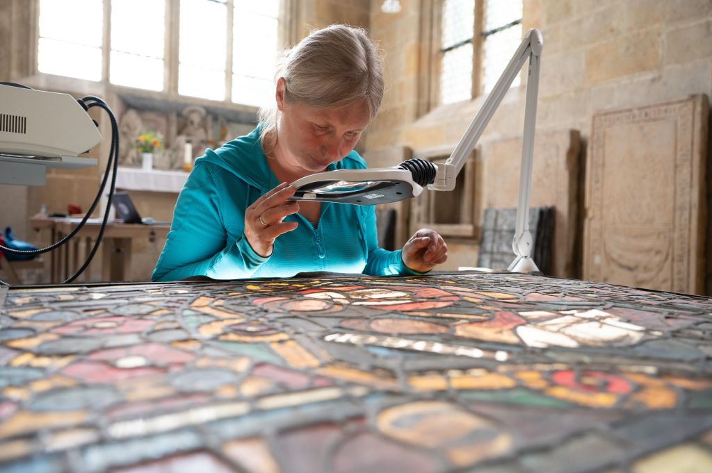 08 August 2023, Saxony, Meißen: Kathrin Rahfoth, certified restorer for stained glass, examines a medieval stained glass window on a light table in Meissen Cathedral. The stained glass window from the cathedral is being scientifically researched and documented as part of the international project "Corpus Vitrearum Medii Aevi". Photo: Sebastian Kahnert/dpa/ZB (Photo by Sebastian Kahnert/picture alliance via Getty Images)
