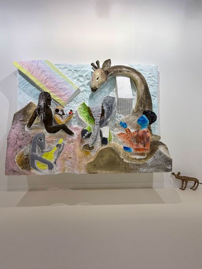 A soft-toned sculpture, made of Styrofoam, bronze, and cardboard featuring humans and animals.