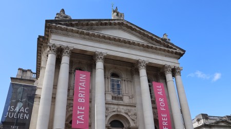A columnated building facade with pink banners hanging down.