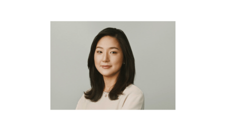 A picture of a woman with dark hair and a light taupe shirt.