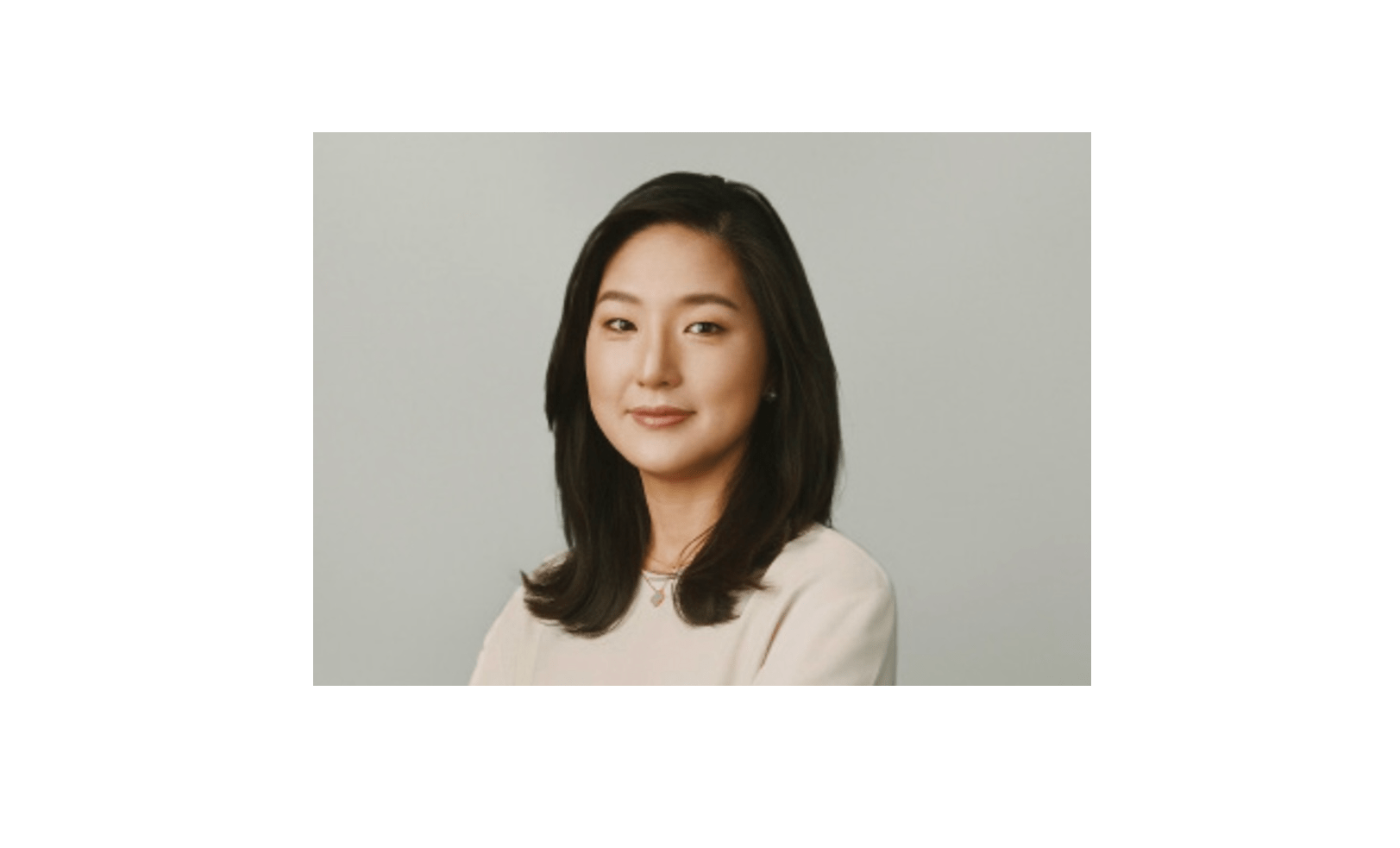 A picture of a woman with dark hair and a light taupe shirt.