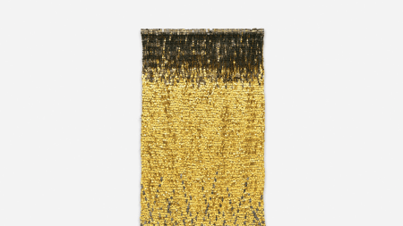 Gold wall hanging against white wall.