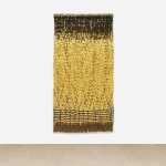 Gold wall hanging against white wall.