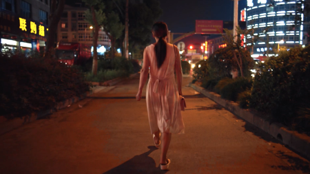 Film still of woman walking through a city at night